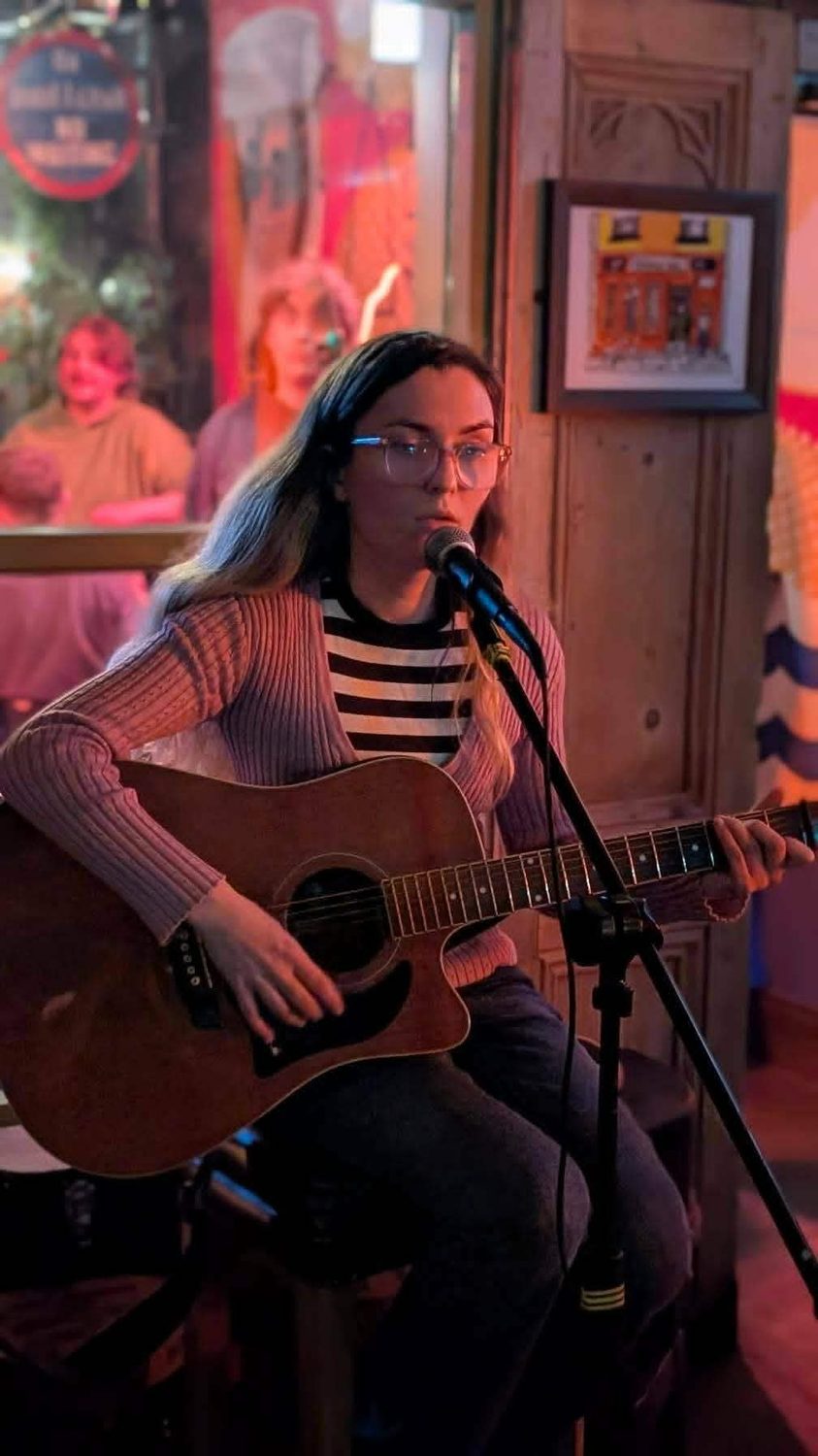 Aimée singing in a warm, lamp-lit pub